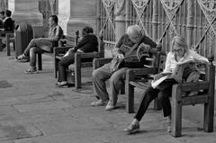 Black and white photo of people sitting on benches and reading in Turin's main square