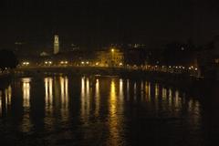 View of Verona at night during Christmas with Adige River, Duomo church tower in the distance, and Vittoria bridge