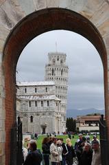 View of Pisa Cathedral and Leaning Tower of Pisa through arch in Medieval walls