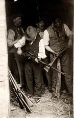 Men in a stable at Windsor Castle Yard with seized firearms, bayonets, and ammunition, London, 1913