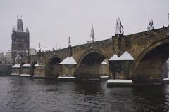 A scenic view of the Vltava River with a castle and snowy landscape