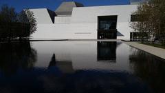 front view of Aga Khan Museum reflected in a black reflecting pond