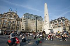 Dam Square in Amsterdam with its notable buildings and bustling activity.