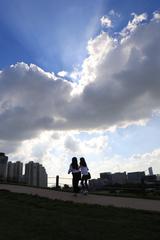 Seoul Olympic Park on a sunny day with lush greenery and tall buildings in the background