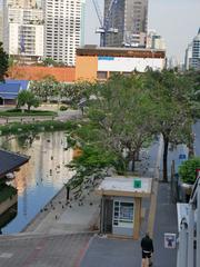 Benjasiri Park in Bangkok with a central lake surrounded by greenery and city buildings in the background