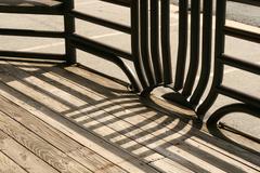 Fancy metal railing casting shadow on wooden deck