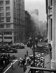 Bradbury Building fire with smoke billowing as firefighters respond and crowd watches in downtown Los Angeles, 1947.