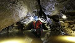 Speleologist observing flooded chamber in Buso della Rana cave