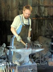 worker hammering a large metal piece on an anvil