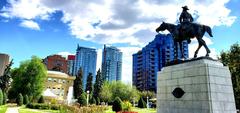 Horseback riding towards a monument in a park with a library in the background