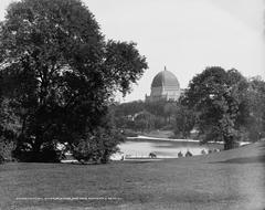 View of Central Park in New York with a boat pond and Temple Beth-El in the background