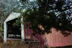 Crooks Covered Bridge over a river surrounded by lush green trees