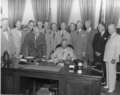 President Harry S. Truman signing the National Security Act Amendments of 1949 in the Oval Office surrounded by officials