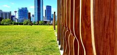 wooden sculptures of people in Fort Calgary with city skyline in background