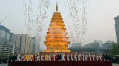 Buddhist monks lighting a stone pagoda-shaped lantern