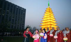 Monks and believers at Lotus Lantern Festival circling stone pagoda lantern in Gwanghwamun Square, Seoul.