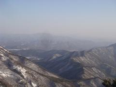 Scenic view of Kyeryongsan mountain with a forest in the foreground and the mountain peaks in the background under a clear blue sky