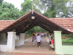 A panoramic view of Hill Palace in Tripunithura with a large white building surrounded by lush greenery and a clear blue sky