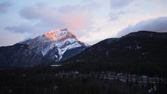 Sunrise touching snow-capped Cascade Mountain in Banff with morning mist