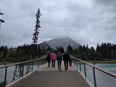 a scenic view of Banff with a clear blue sky, green pine trees, and majestic mountains