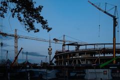 Construction site of the SAP Garden with tower cranes and Olympic tower at twilight