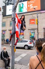 A person hanging a Canada Flag on a light post on Canada Day