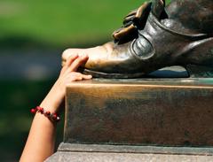 Closeup of hand rubbing John Harvard statue's toe