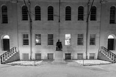 statue of John Harvard at Harvard University campus at night