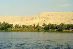 Nile cruise boat on the river with Esna cityscape in the background