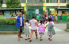 schoolchildren assisted by a village watchman crossing the road