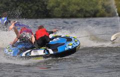 Jet ski towing a doughnut with people holding on