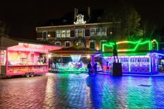 Funfair lights reflecting on wet cobblestones at night in Fives,