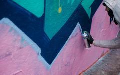 Artist spray painting graffiti on a wall in Leake Street, London