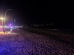 Jimbaran beach at night with restaurants on the left and GWK statue in the background