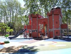 Castillet playground view showing benches and colorful play structures surrounded by trees