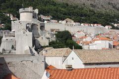 Panoramic view of Dubrovnik's historic old town with its red-tiled roofs and surrounding city walls under a clear blue sky