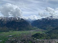 A picturesque landscape of Interlaken, Switzerland with mountains, greenery, and clear blue sky