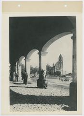 A man leaning on an archway column in early 20th century Mexico