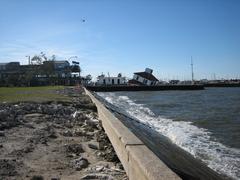 Scours in Lakefront Park levee along Lake Pontchartrain after Hurricane Katrina, with collapsed New Basin Canal lighthouse and helicopter in the distance