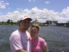 Couple standing on the jetty at West End, New Orleans with New Basin Canal Lighthouse and Yacht Club building in the background