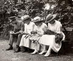 Visitors at Artis Zoo: three young women in white clothing with hats on a bench with a young man in uniform