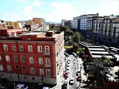 Piazza Cavour in Naples showcasing historic and modern architecture, including the red Pompeian station 'Museo' of Metro Line 1.