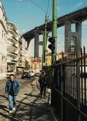 Street in Lisbon with 25th of April Bridge in background