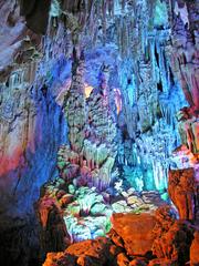 Colorfully illuminated Reed Flute Cave interior with stalactites, stone pillars, and rock formations