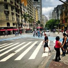 People walking and crossing the pedestrian lane at the intersection of Avenida Ipiranga with Avenida São João in São Paulo city center