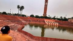 Clock tower of Lucknow with a gold bird on top and an ancient water pool in the foreground