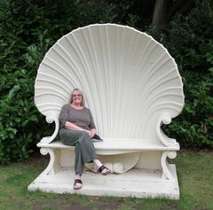 Linda sitting on Walpole's Shell Bench in a garden