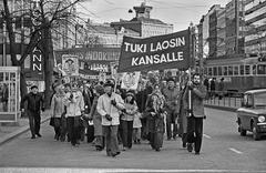 Protesters marching on Mannerheimintie road near Kolmensepänaukio with banners supporting Laos and calling for the USA to leave Indochina