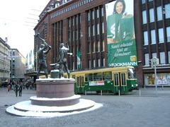 A tram passes by the three smiths statue in central Helsinki