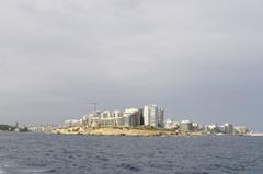 coastal view of a Maltese town with traditional buildings and green landscape